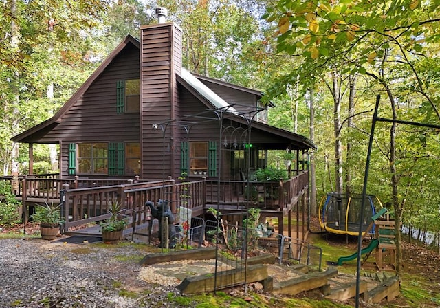 back of house with a trampoline and a wooden deck