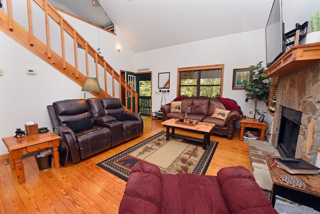 living room with a fireplace, light hardwood / wood-style flooring, and high vaulted ceiling