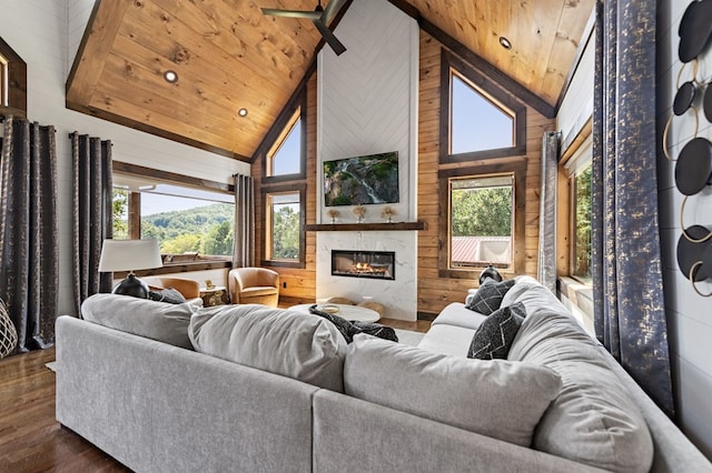 living room with high vaulted ceiling, wooden walls, a large fireplace, dark wood-type flooring, and wooden ceiling