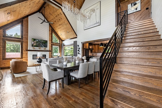 dining room featuring high vaulted ceiling, plenty of natural light, wood walls, and hardwood / wood-style flooring