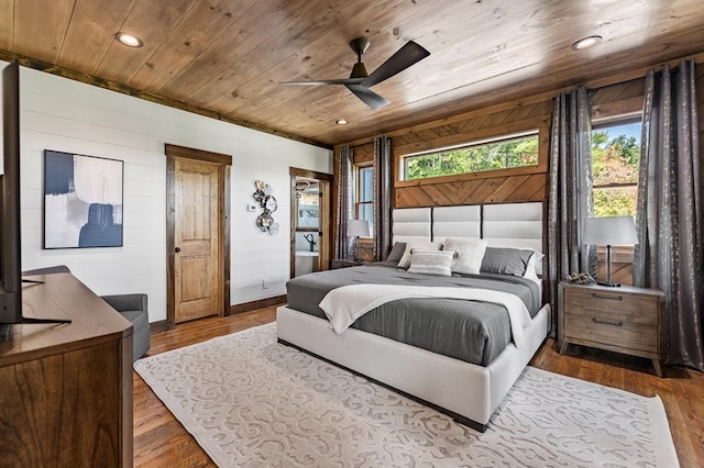 bedroom featuring wood walls, wood ceiling, hardwood / wood-style flooring, and ceiling fan