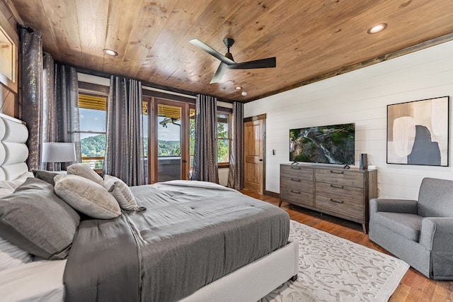 bedroom with ceiling fan, wooden ceiling, wood-type flooring, and wooden walls