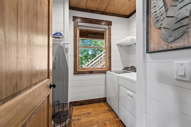 clothes washing area with hardwood / wood-style flooring, wooden walls, washer and clothes dryer, and wood ceiling