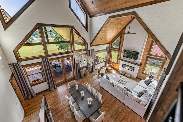 living room with wood walls, plenty of natural light, and high vaulted ceiling