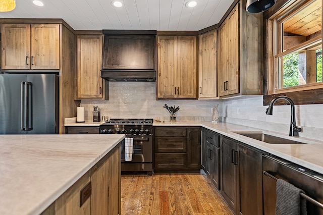 kitchen featuring wood-type flooring, high end appliances, sink, tasteful backsplash, and custom range hood