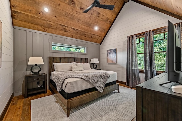 bedroom featuring wood-type flooring, multiple windows, wooden walls, and lofted ceiling