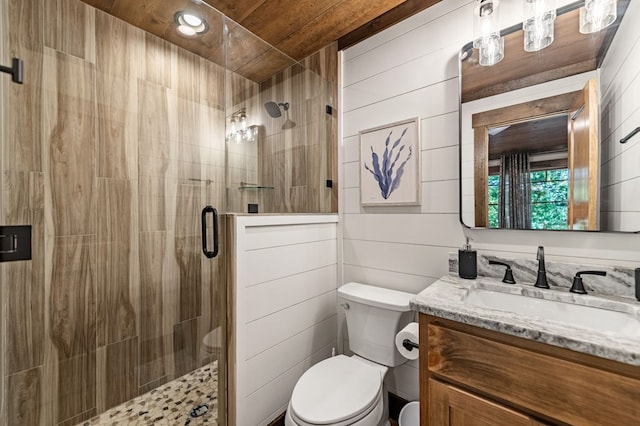 bathroom with wood walls, a shower with shower door, vanity, and toilet