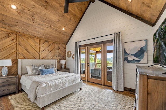 bedroom featuring wood walls, light hardwood / wood-style floors, access to exterior, and high vaulted ceiling