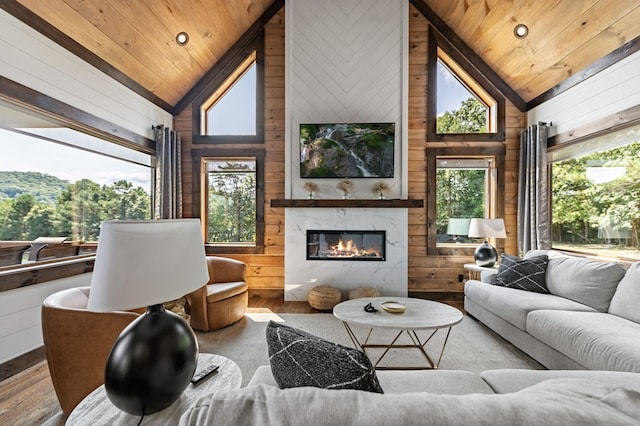 living room with wood walls, wooden ceiling, a fireplace, and high vaulted ceiling