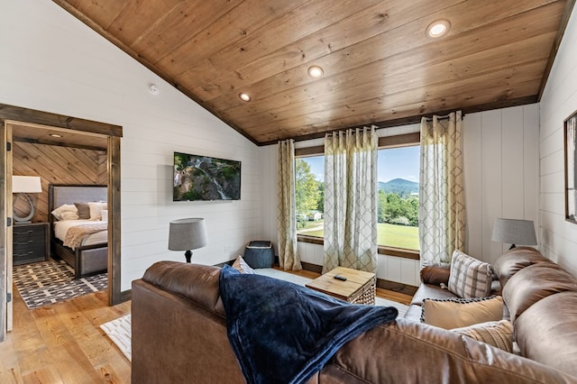 living room with light hardwood / wood-style floors, lofted ceiling, wooden walls, wooden ceiling, and a mountain view