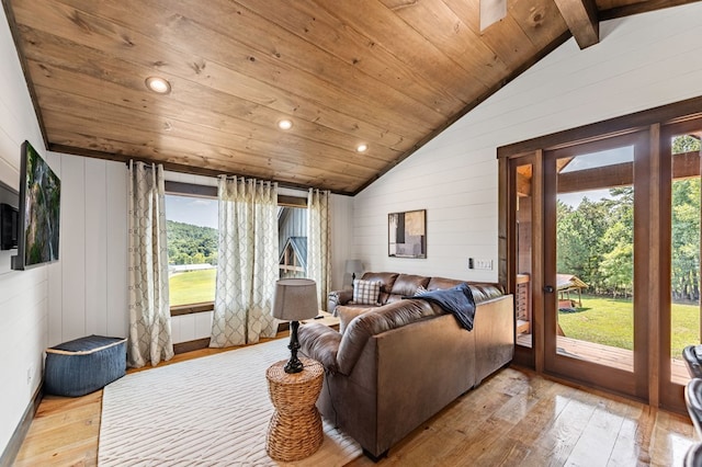 living room with light hardwood / wood-style flooring, vaulted ceiling with beams, and plenty of natural light