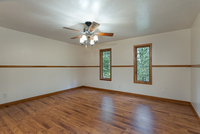 spare room featuring visible vents, ceiling fan, a textured ceiling, wood finished floors, and baseboards