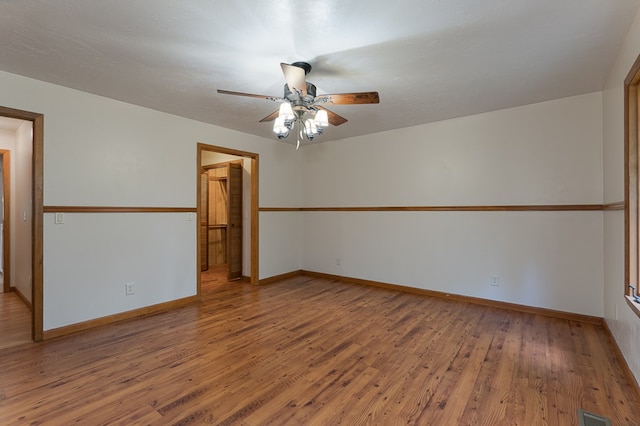 spare room featuring ceiling fan, wood finished floors, visible vents, and baseboards