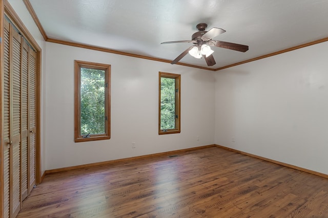 unfurnished bedroom with a ceiling fan, crown molding, baseboards, and wood finished floors