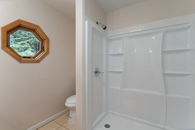 bathroom featuring toilet, a shower stall, baseboards, and tile patterned floors