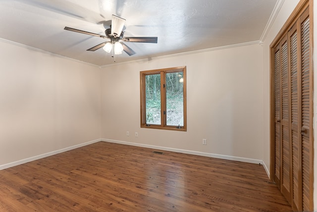 unfurnished bedroom featuring a closet, baseboards, dark wood finished floors, and crown molding