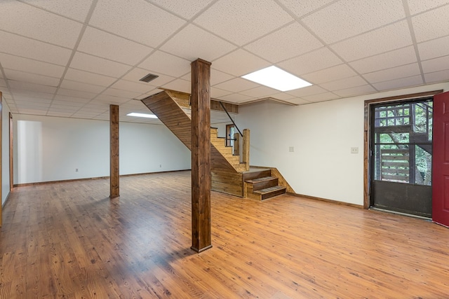 basement featuring a paneled ceiling, visible vents, wood finished floors, baseboards, and stairs