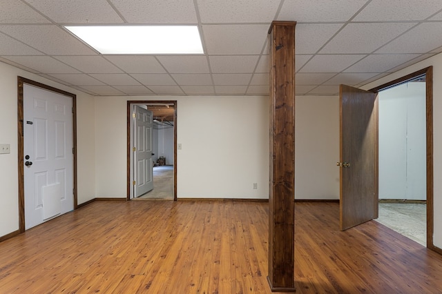 finished basement featuring a drop ceiling, wood finished floors, and baseboards