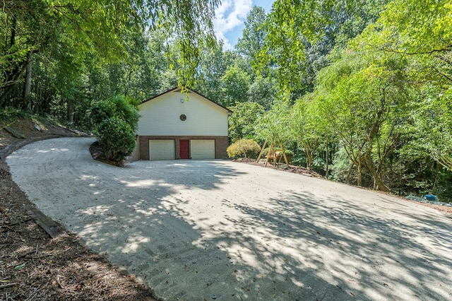 garage featuring driveway and a wooded view