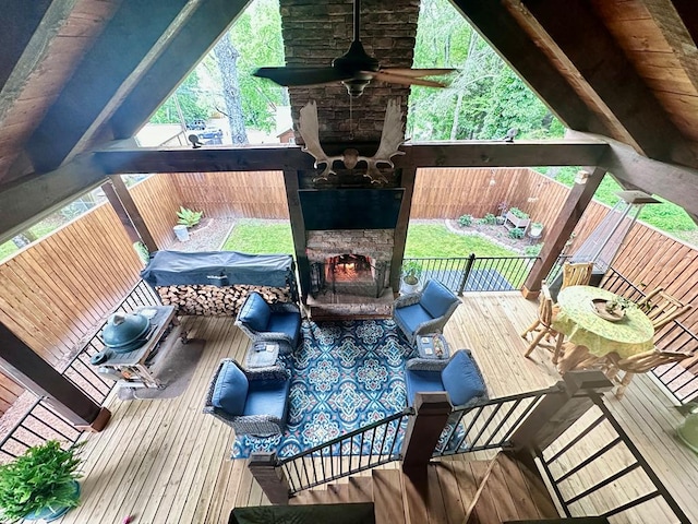 wooden deck with an outdoor stone fireplace and a fenced backyard