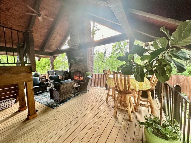 sunroom featuring an outdoor stone fireplace and vaulted ceiling with beams