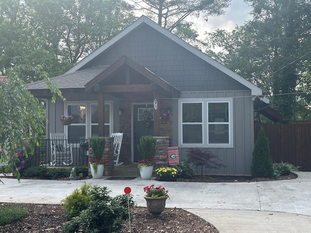 view of front of house featuring board and batten siding, a porch, and fence