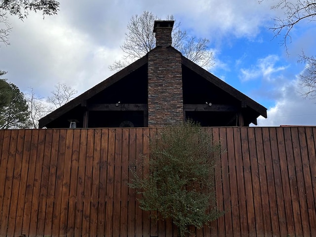 view of side of home with fence and a chimney