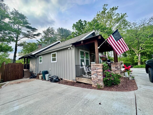 exterior space featuring board and batten siding, a shingled roof, and a chimney