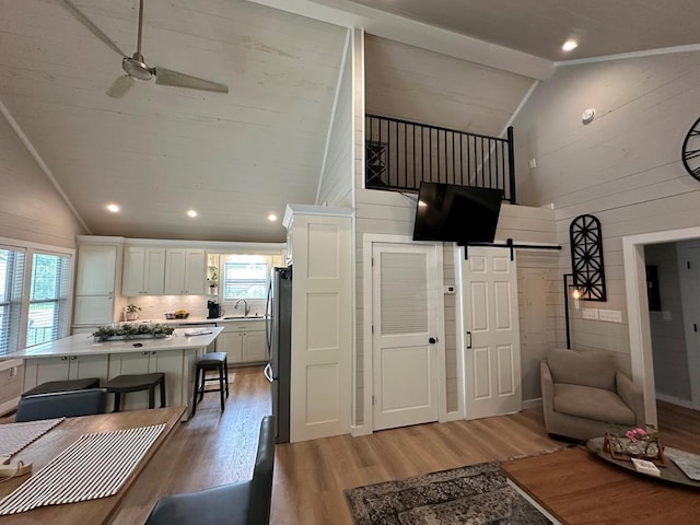 interior space with a center island, light wood finished floors, light countertops, a barn door, and freestanding refrigerator