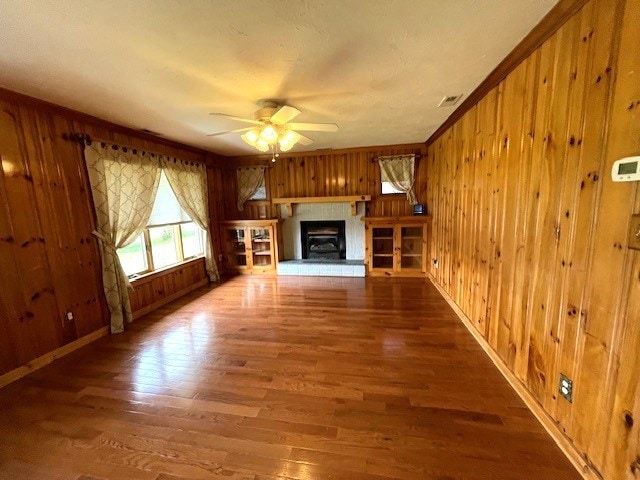 unfurnished living room featuring dark wood-type flooring, ceiling fan, and wood walls