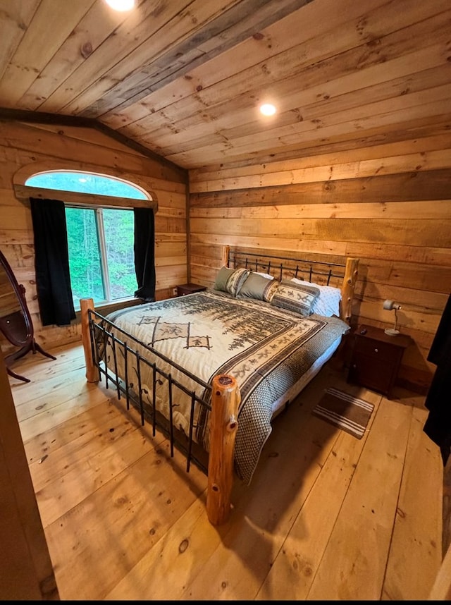 bedroom with lofted ceiling, light hardwood / wood-style flooring, wooden ceiling, and wood walls