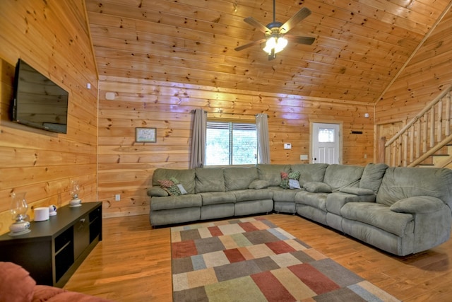 living area with wood finished floors, wooden walls, lofted ceiling, wood ceiling, and stairs