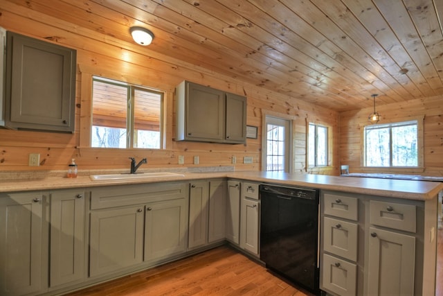 kitchen with wood walls, dishwasher, a peninsula, and a sink