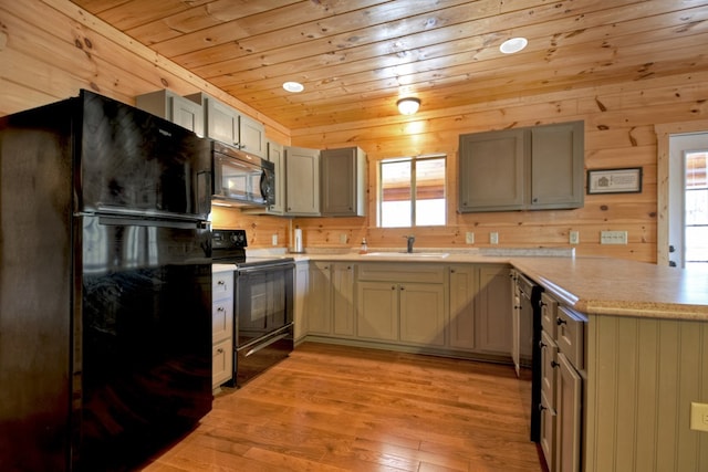 kitchen with light wood finished floors, a peninsula, a sink, black appliances, and wooden ceiling