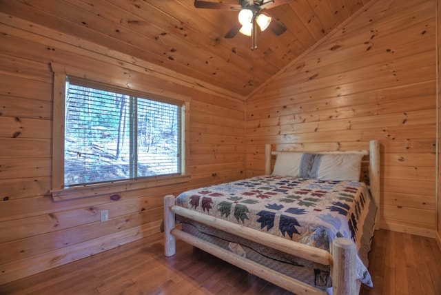 bedroom with wooden walls, wood finished floors, and vaulted ceiling