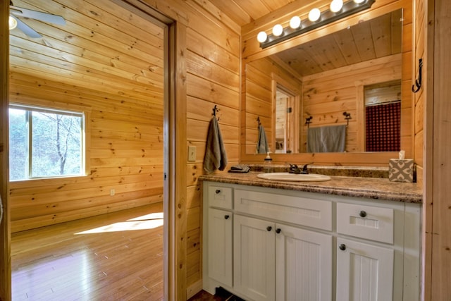 bathroom with wood walls, wooden ceiling, vanity, and wood finished floors