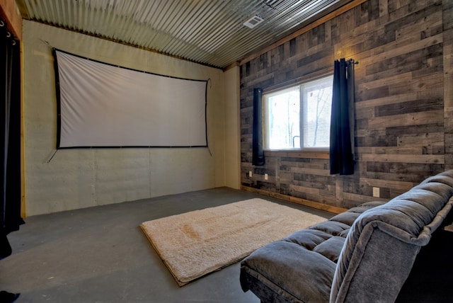 home theater room featuring wooden walls and concrete floors