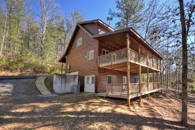 back of property featuring central air condition unit, a wooden deck, and log veneer siding