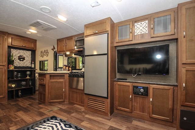 85 27th St, Ellijay, GA 30540 - kitchen with freestanding refrigerator, stainless steel microwave, brown cabinetry, dark wood-style floors, and glass insert cabinets