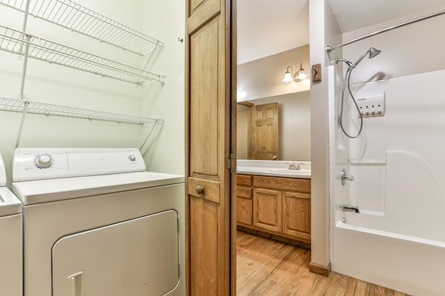 laundry area featuring sink, washer and dryer, and light wood-type flooring