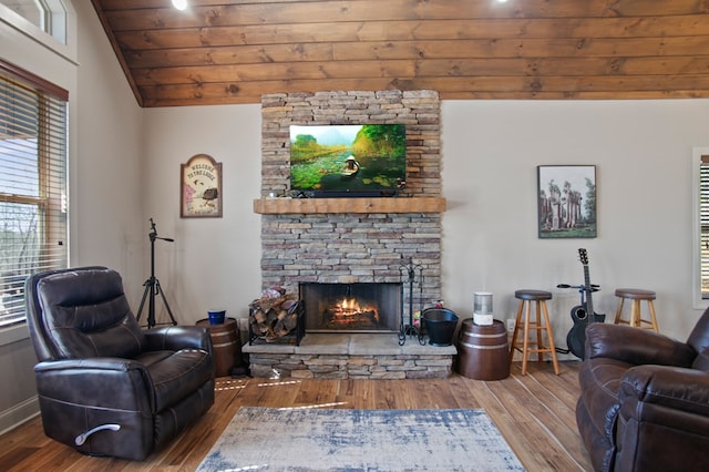 living room featuring baseboards, wooden ceiling, wood finished floors, vaulted ceiling, and a stone fireplace