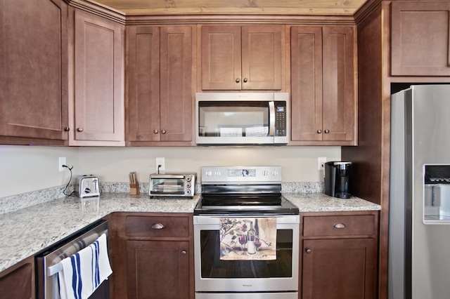 kitchen featuring stainless steel appliances, light stone counters, brown cabinetry, and a toaster