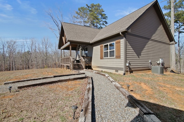 view of side of home with roof with shingles, crawl space, and central air condition unit