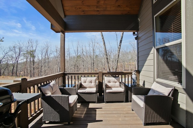 wooden deck featuring outdoor lounge area, grilling area, and a wooded view