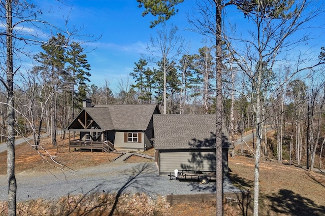 rustic home featuring a chimney, roof with shingles, driveway, and a deck