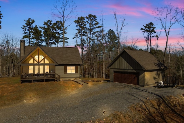 view of front of home featuring a garage, a chimney, an outbuilding, and a wooden deck