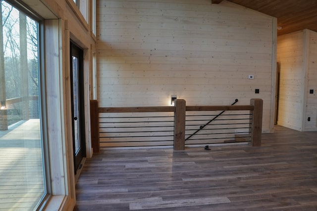 corridor featuring dark wood-type flooring, lofted ceiling, and wooden walls