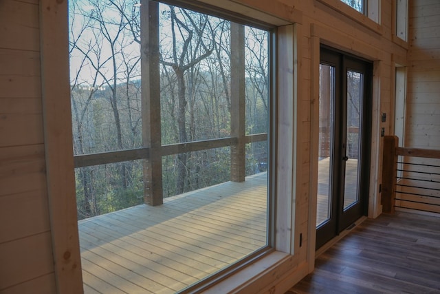 doorway to outside with a wealth of natural light, dark hardwood / wood-style floors, wooden walls, and french doors