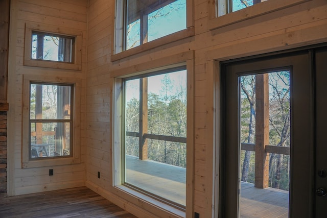 entryway featuring hardwood / wood-style flooring, wooden walls, and a high ceiling