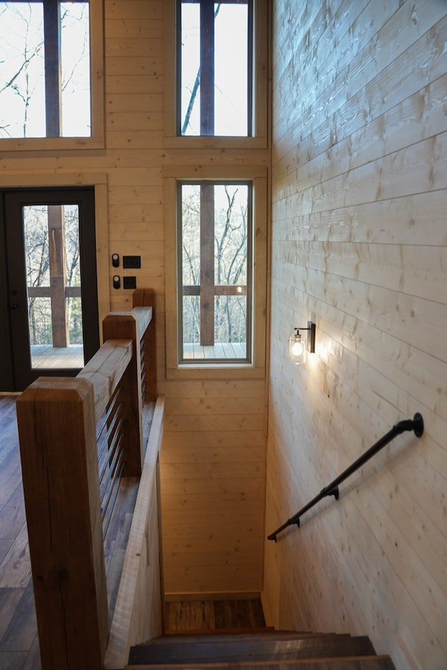 stairway with a towering ceiling, plenty of natural light, and wood walls